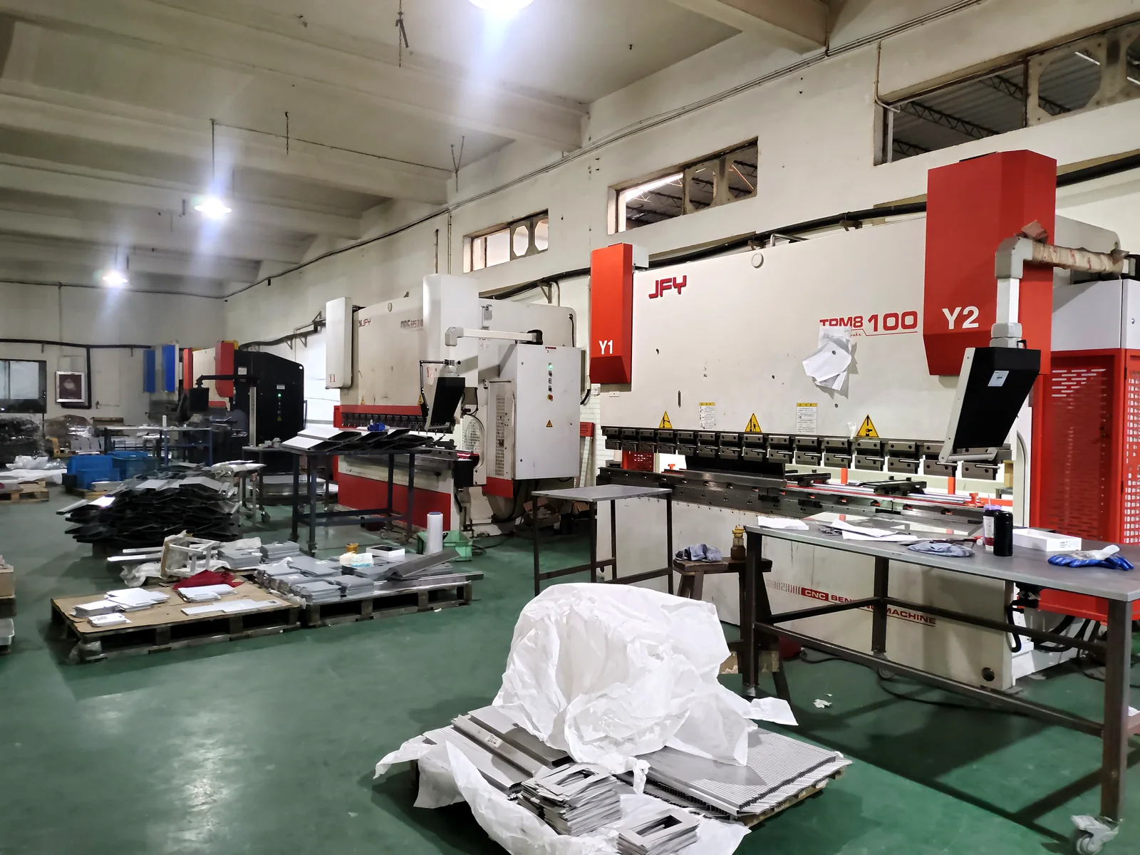 Fulei Metal sheet metal fabrication workshop in Ningbo, China, showing the CNC press brake bending station and prepared stainless steel parts