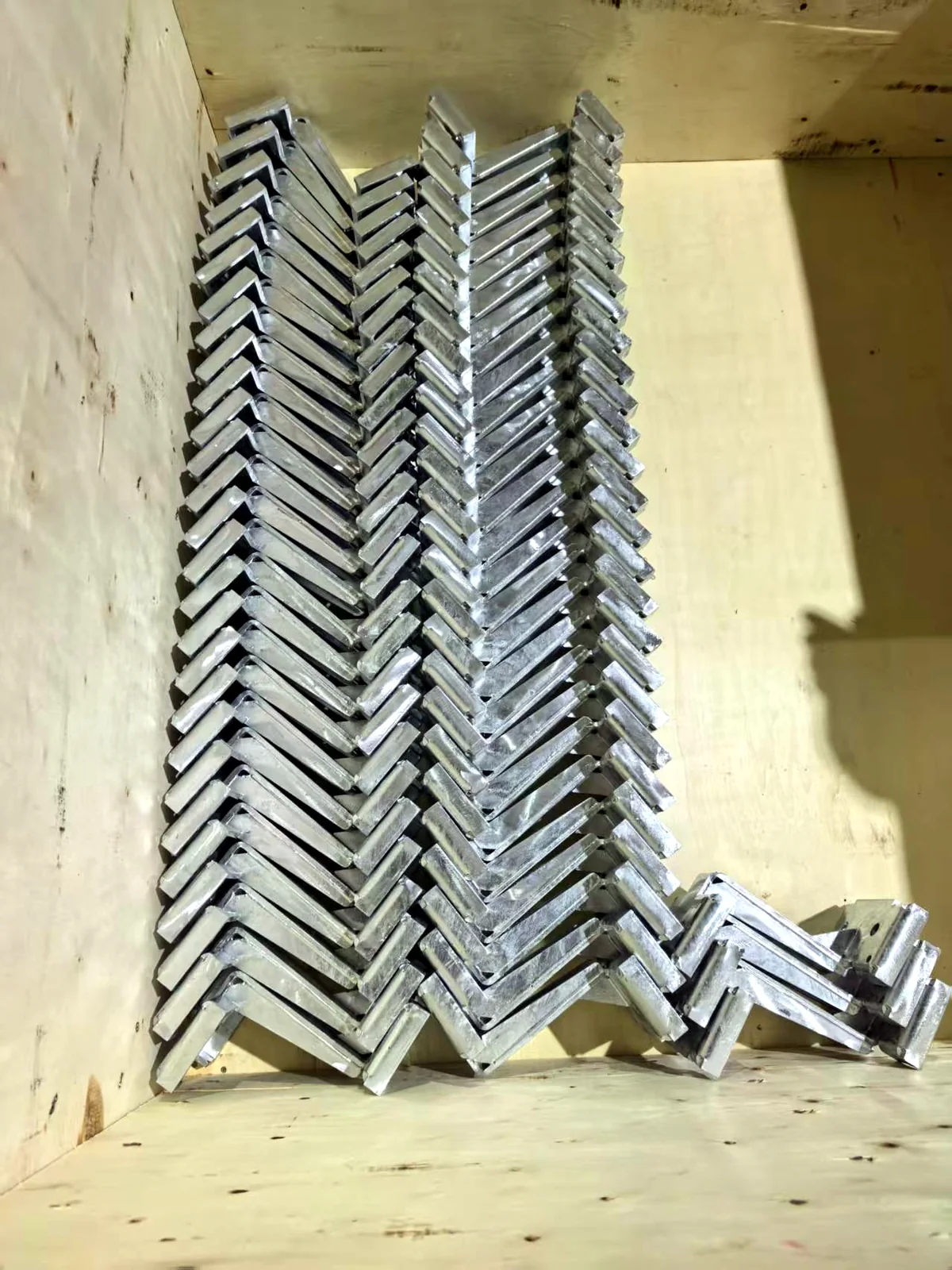 Galvanised steel brackets separated and stacked in a plywood export crate before shipment