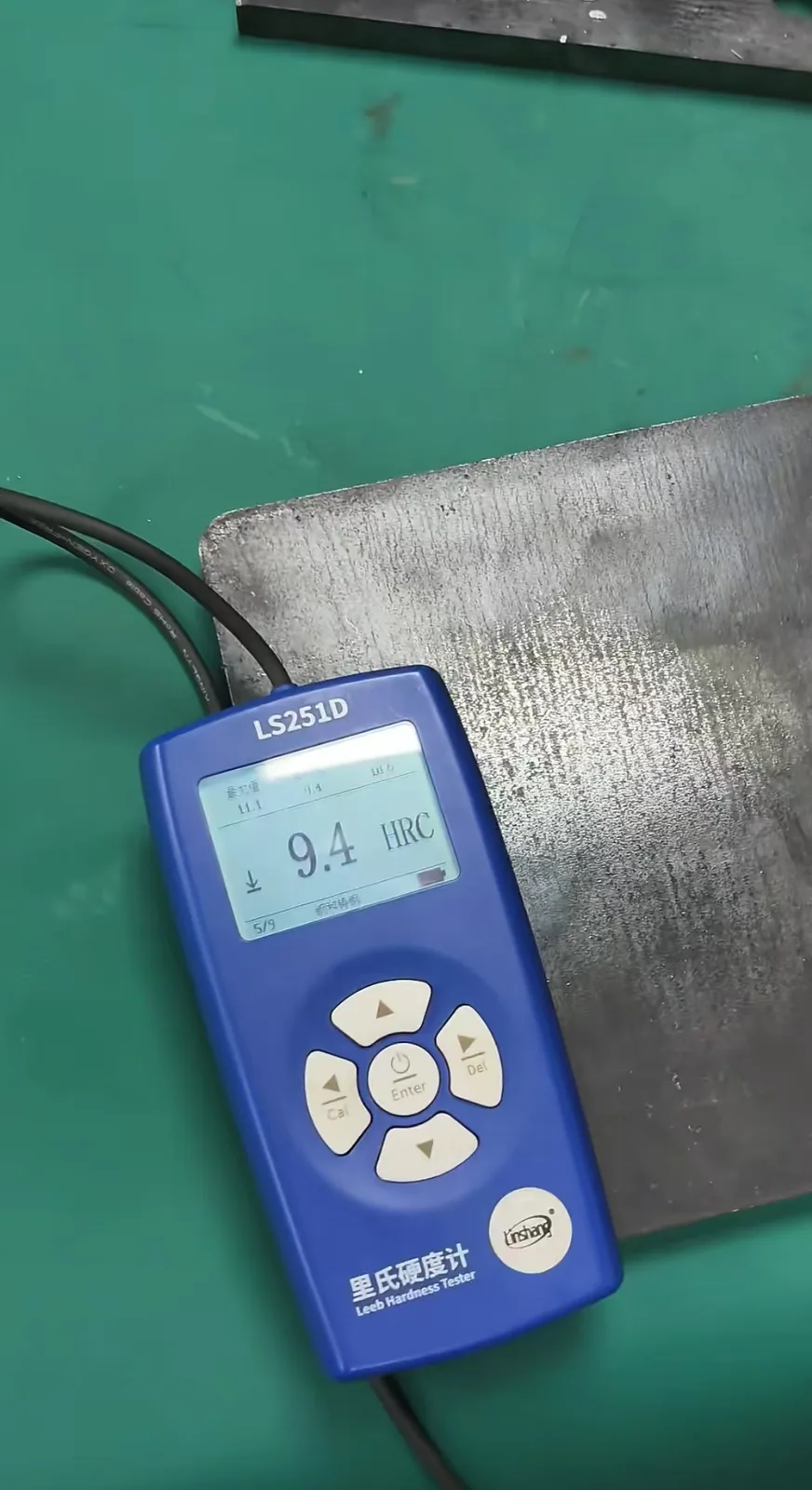 Leeb hardness tester showing a live HRC reading on a steel test block