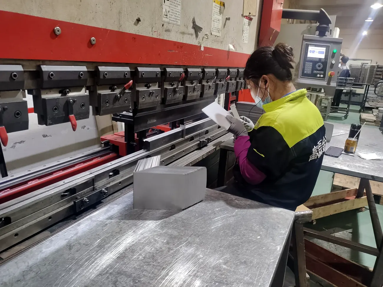 CNC press brake operator checking a formed sheet metal part against the drawing at Fulei Metal