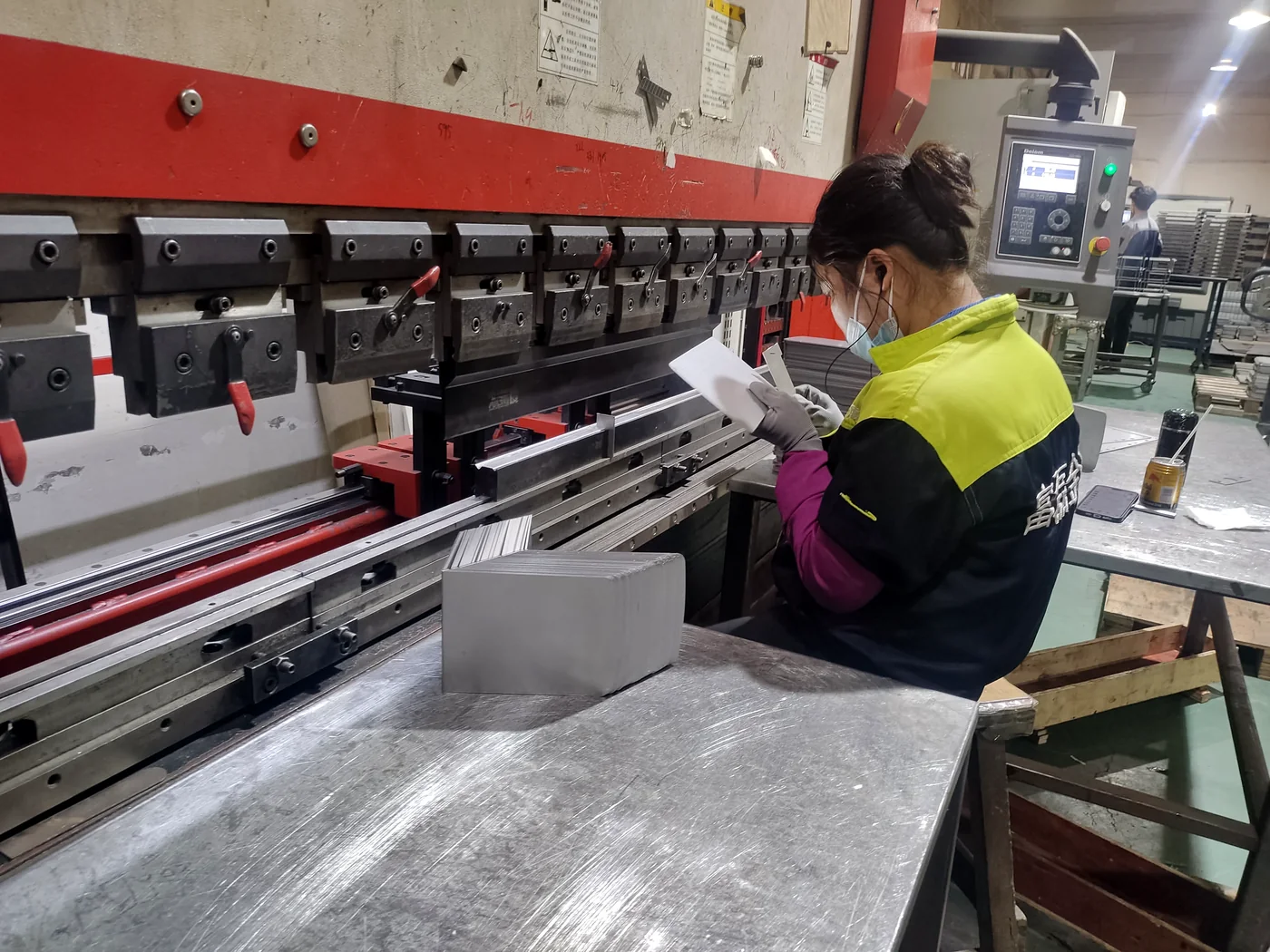 CNC press brake operator checking a formed sheet metal part against the drawing at Fulei Metal