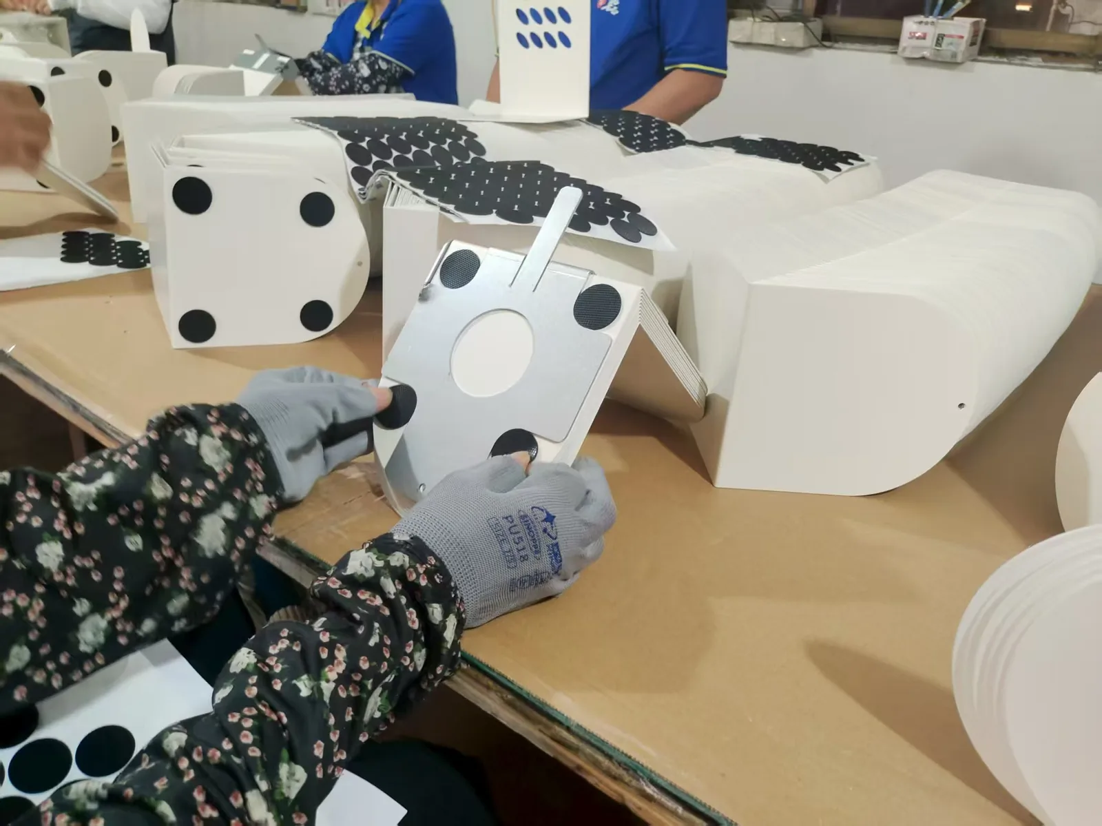 Operator fitting self-adhesive rubber pads to a fabricated enclosure base during final assembly